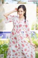 A woman in a white dress with red flowers on it.