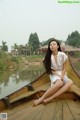 A woman sitting on a wooden boat on a lake.