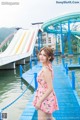 A woman in a pink dress standing on a dock next to a water slide.