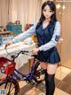 A woman in a school uniform standing next to a bike.