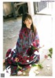 A woman sitting on the ground with flowers around her.