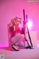 A woman in a pink outfit holding a pink gun.