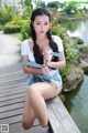 A woman sitting on a wooden dock next to a body of water.