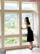 A woman standing in front of a large window.