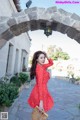 A woman in a red polka dot dress is posing for a picture.