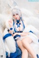 A woman in a blue and white outfit sitting on a white couch.