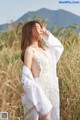 A woman in a white dress standing in a field.