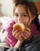 A young woman eating a hamburger on a bed.