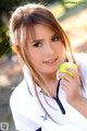 A young woman holding a tennis ball in her hand.