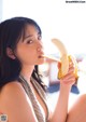 A woman sitting on the floor eating a banana.