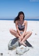 A woman sitting on a rock on the beach.