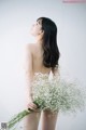 A naked woman holding a bunch of baby's breath.