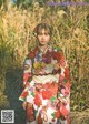 A woman in a colorful kimono standing in a field.