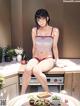 A woman in a bikini sitting on a kitchen counter.